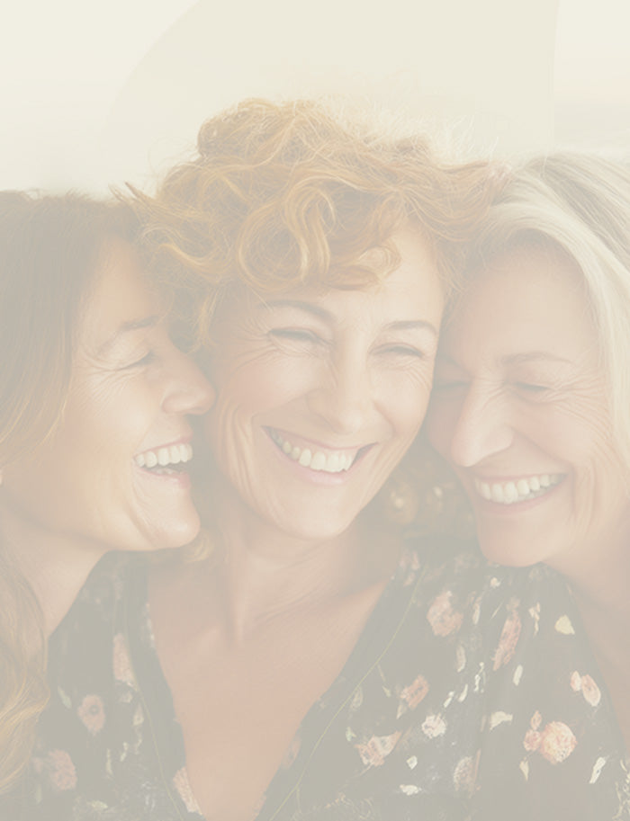 Three women smiling closely together with a light overlay