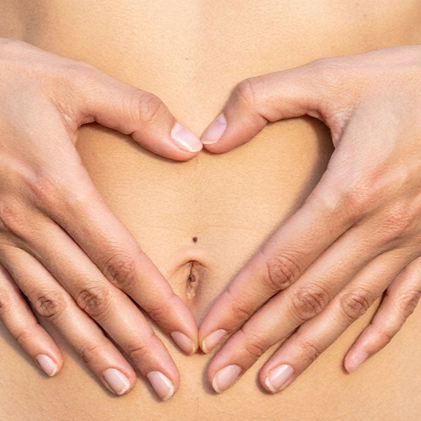 Hands forming a heart shape over a belly button