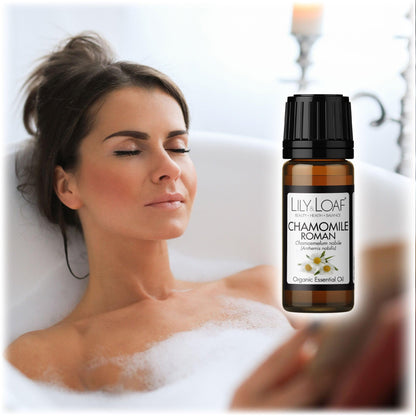 Woman relaxing in a bubble bath with eyes closed, alongside Lily & Loaf Chamomile Roman Organic Essential Oil bottle. Promotes relaxation and stress relief.