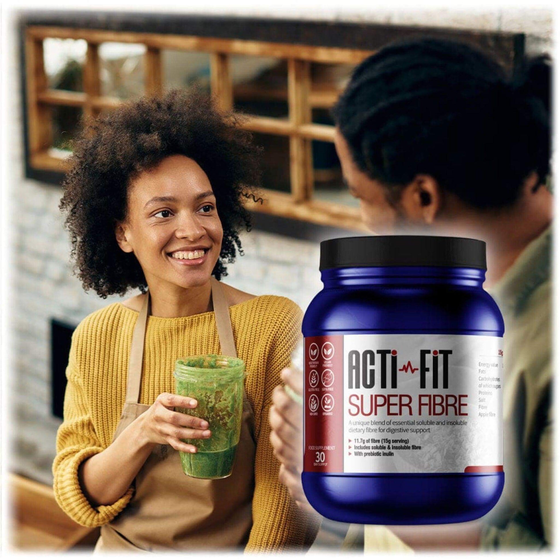 Two people smiling in a kitchen, sharing a green smoothie, with Acti-Fit Super Fibre tub shown alongside for daily fibre support.